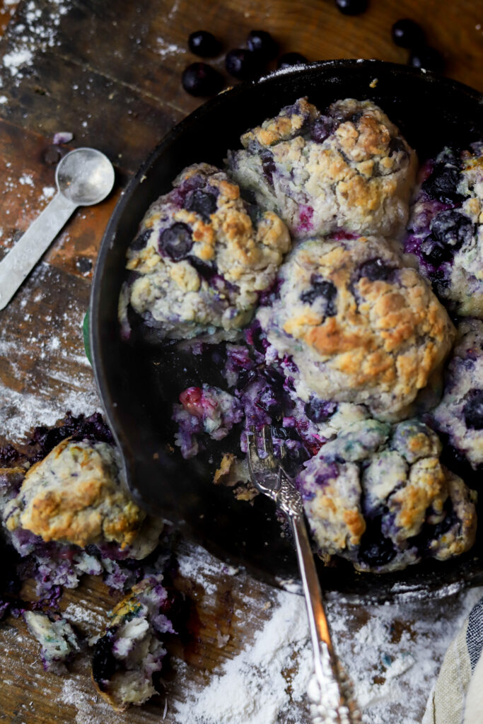 These country blueberry biscuits are literally so delicious and easy to make. I feel like these are really the old-fashioned way to make cathead biscuits. Instead of butter, you'll use shortening then mix together your flour, baking soda, sugar, and of course buttermilk. Knead them all together with some frozen blueberries into balls and bake them in a skillet with some melted butter for about 20 minutes until golden brown. These are the perfect breakfast or perfect for even just a snack. 