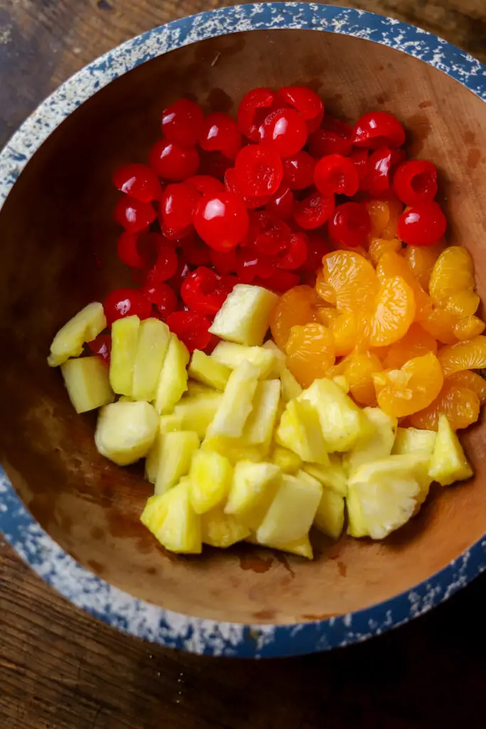 This ambrosia fruit salad with cool whip. Classic potluck dessert. It's so simple and takes less than 5 minutes to throw together. It's a fruit cocktail of mandarin oranges, pineapple, and cherries mixed with coconut flakes and crushed pecans. If you love a cool whip and marshmallow fruit salad, this is the one, right here.