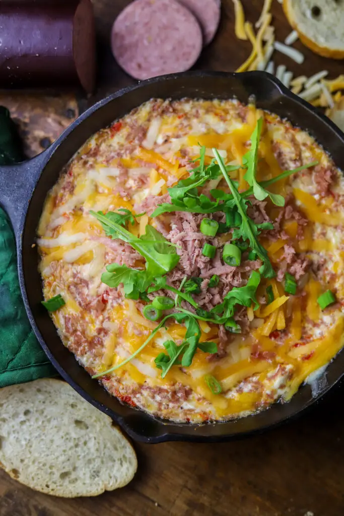 This baked summer sausage cheese dip. Mhmm. Perfect cheesy skillet appetizer. Kind of the same concept of a dried beef dip or appetizer, you'll take a summer sausage roll, chop it or grate it up, mix with some cheddar, cream cheese, pimentos and spices. Bake and serve. This is the most savory dip that is so good and perfect for any occasion.
