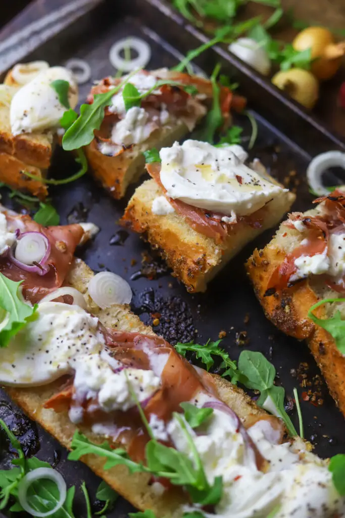 This burrata toast with honey and prosciutto. Mhmmm. The best of the burrata appetizers. It’s a big loaf of Italian seasoned bread cut in half and topped with prosciutto, honey, onions baked until it’s crispy. Top it off with more honey, fresh burrata and arugula. Crack some black pepper and red pepper flakes for the best toasty appetizer. 