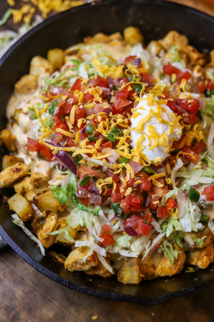 This loaded chicken and potato Mexican skillet is a perfect quick dinner. It's like a spin on loaded nachos and a Mexican hash. It's sauteed chicken and potatoes in some taco seasonings until they are both fully cooked and tender. You'll then mix up some queso and pour over them and top off with cheeses, garnish, pico de gallo, sour cream and more!