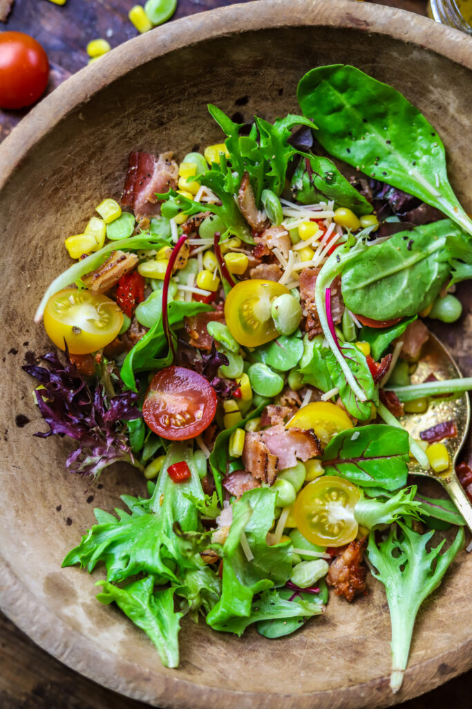 This corn succotash salad is perfect for a meal or for a side. It's packed with fresh greens, corn, baby lima beans, pimentos and bacon. Top it with a homemade sweet onion dressing to finish. This salad just screams Southern comfort thrown into a fresh and light salad.