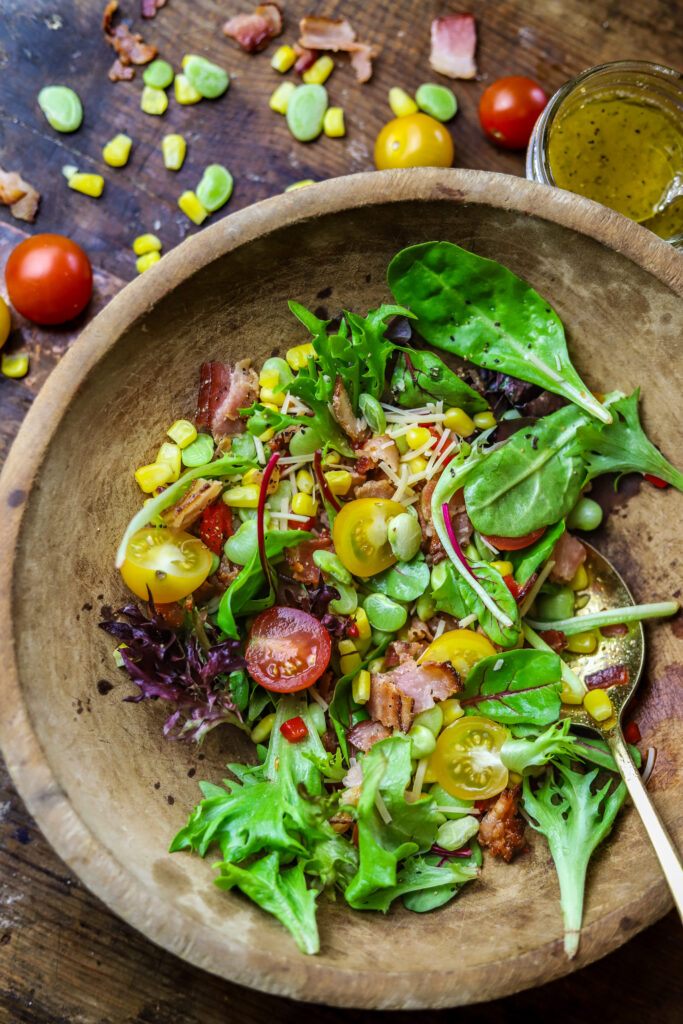 This corn succotash salad is perfect for a meal or for a side. It's packed with fresh greens, corn, baby lima beans, pimentos and bacon. Top it with a homemade sweet onion dressing to finish. This salad just screams Southern comfort thrown into a fresh and light salad.