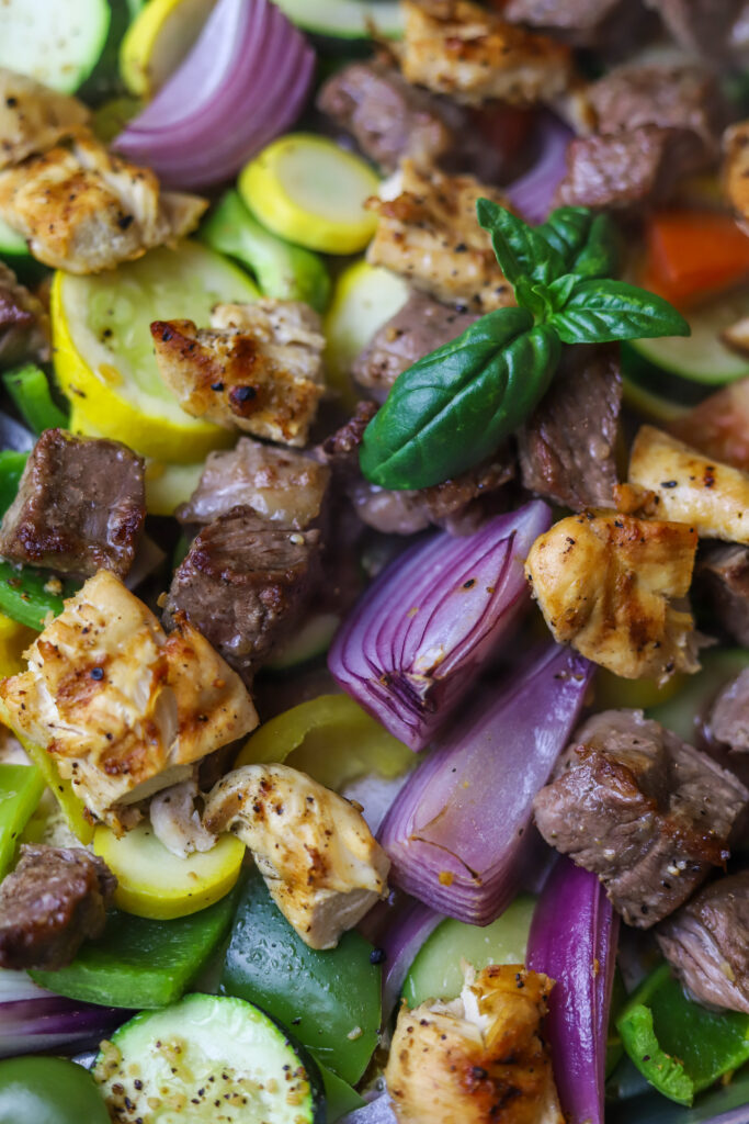 These sheet pan kabobs in the oven are perfect weeknight meal. So, we’re really not re-inventing the wheel here with this recipe. There’s not much to it. First, you’re going to sauté some steak until it’s seared on the outside and then fully cook some chicken. Cut them into pieces and put them on a sheet pan with various vegetables of your choice. I love onions and squash and peppers. Give it all a good douse of olive oil and seasoning and bake for around 20 minutes until vegetables are soft and meat is cooked in the center. This recipe is easy, quick and mess-free.