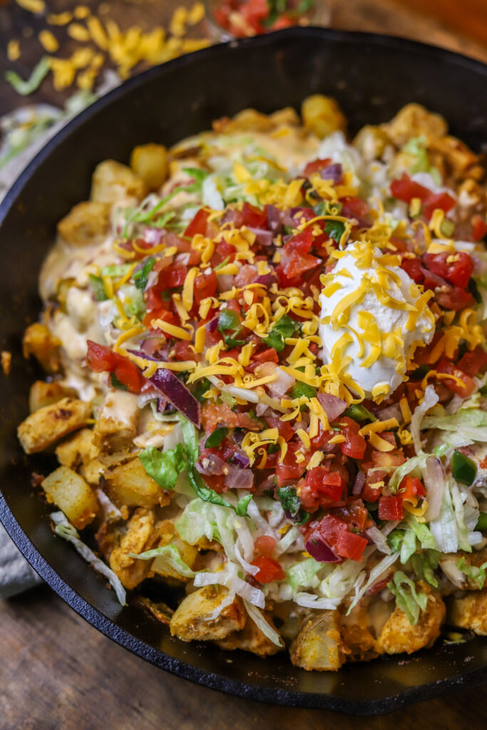 This loaded chicken and potato Mexican skillet is a perfect quick dinner. It's like a spin on loaded nachos and a Mexican hash. It's sauteed chicken and potatoes in some taco seasonings until they are both fully cooked and tender. You'll then mix up some queso and pour over them and top off with cheeses, garnish, pico de gallo, sour cream and more!