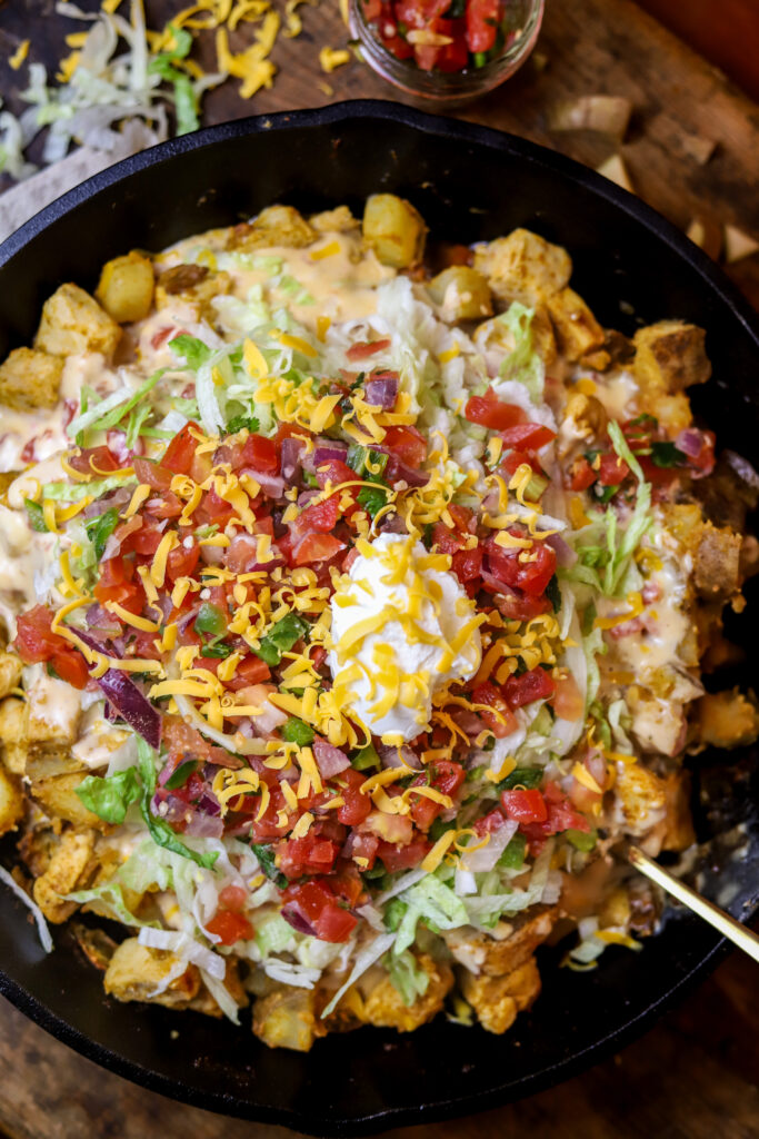 This loaded chicken and potato Mexican skillet is a perfect quick dinner. It's like a spin on loaded nachos and a Mexican hash. It's sauteed chicken and potatoes in some taco seasonings until they are both fully cooked and tender. You'll then mix up some queso and pour over them and top off with cheeses, garnish, pico de gallo, sour cream and more!