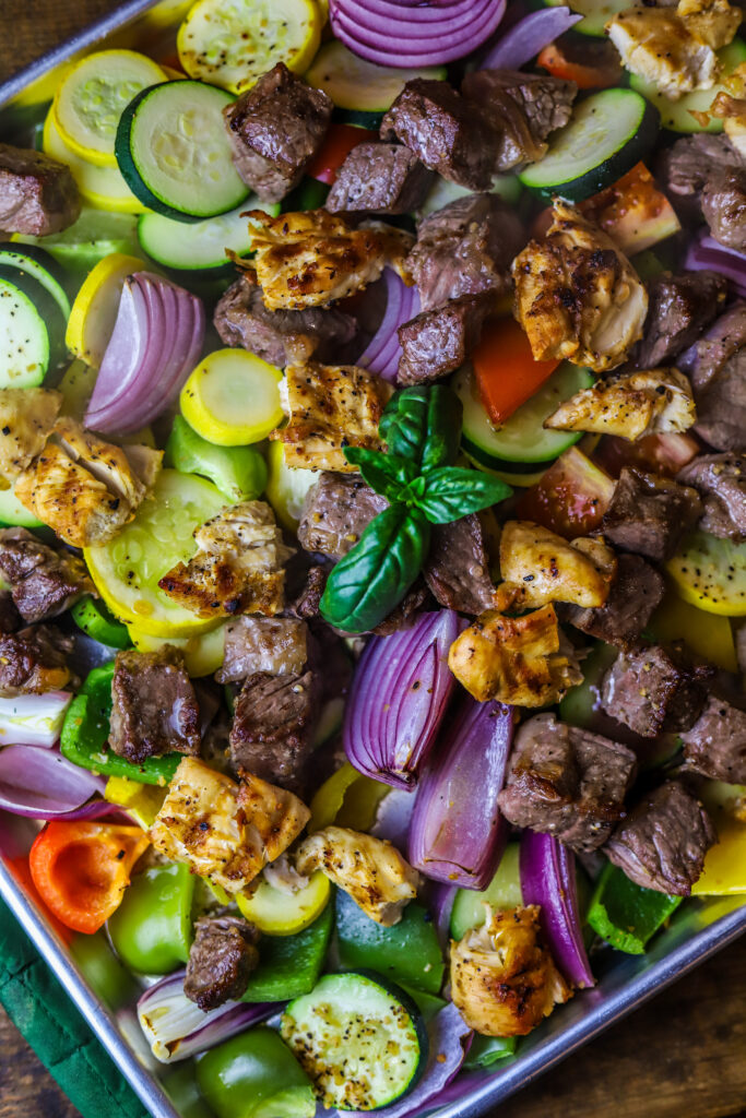 These sheet pan kabobs in the oven are perfect weeknight meal. So, we’re really not re-inventing the wheel here with this recipe. There’s not much to it. First, you’re going to sauté some steak until it’s seared on the outside and then fully cook some chicken. Cut them into pieces and put them on a sheet pan with various vegetables of your choice. I love onions and squash and peppers. Give it all a good douse of olive oil and seasoning and bake for around 20 minutes until vegetables are soft and meat is cooked in the center. This recipe is easy, quick and mess-free.