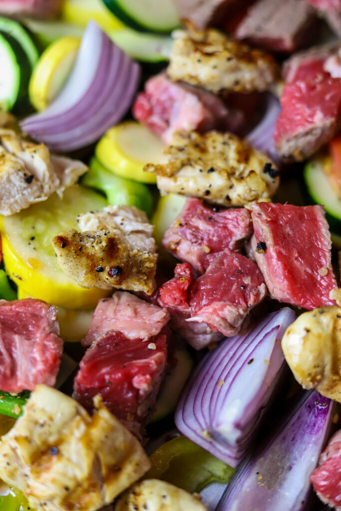 These sheet pan kabobs in the oven are perfect weeknight meal. So, we’re really not re-inventing the wheel here with this recipe. There’s not much to it. First, you’re going to sauté some steak until it’s seared on the outside and then fully cook some chicken. Cut them into pieces and put them on a sheet pan with various vegetables of your choice. I love onions and squash and peppers. Give it all a good douse of olive oil and seasoning and bake for around 20 minutes until vegetables are soft and meat is cooked in the center. This recipe is easy, quick and mess-free.