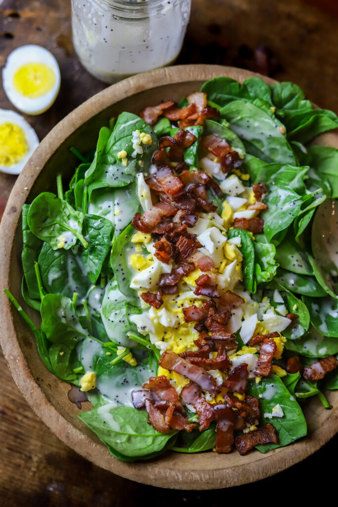 This spinach salad with bacon and eggs is a perfect blend of savory and sweet. The flavors of the salty bacon pair so well with the boiled egg and creamy poppyseed dressing. The dressing is so sweet and flavorful and super easy to make. You can't beat throwing together a salad with essentially 4 ingredients that's packed with flavor.