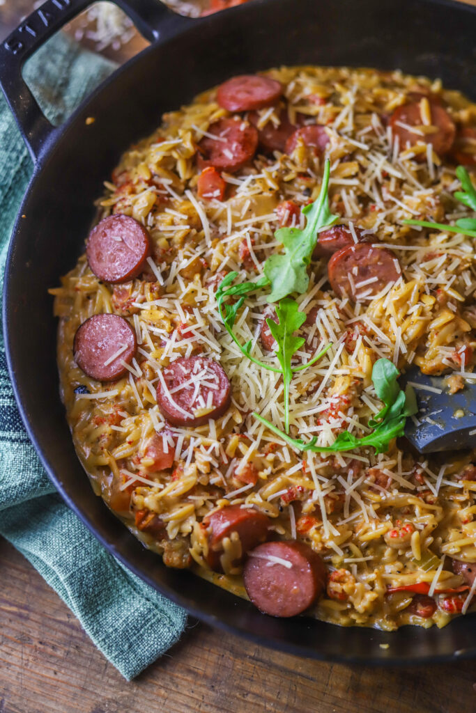 This Cajun creamy orzo recipe. It's so delicious. It's a spicy tomato base with crawfish tails. Add your orzo with some broth and let it all cook until your pasta is nice and tender. Fold in heavy cream, parmesan and browned smoked sausage. This one-pot meal is so simple and delicious and takes less than 30 to make. 