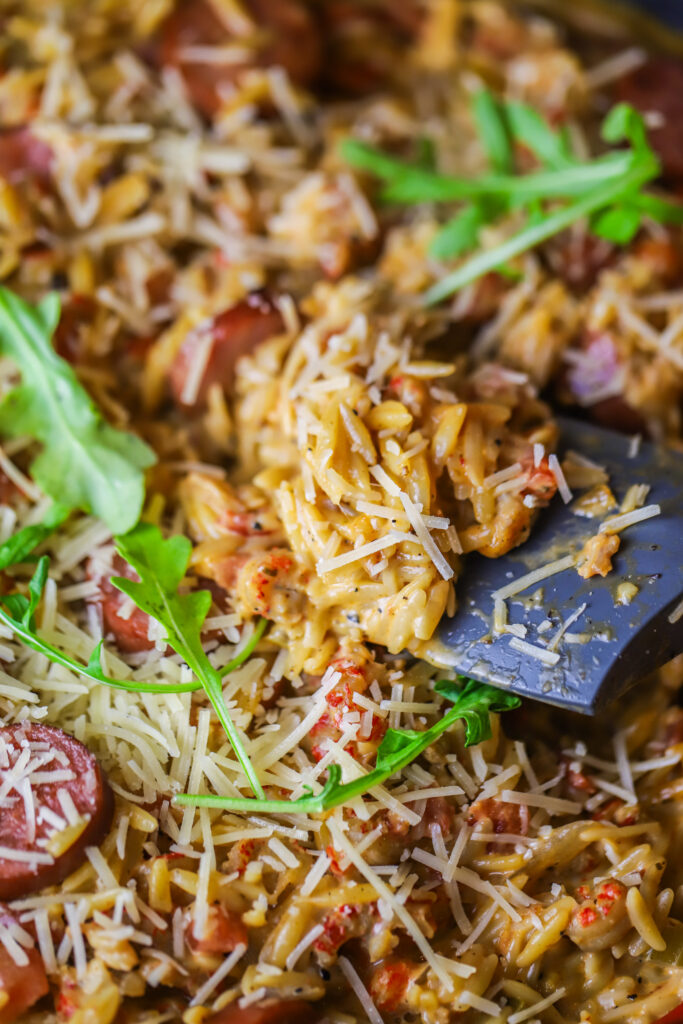 This Cajun creamy orzo recipe. It's so delicious. It's a spicy tomato base with crawfish tails. Add your orzo with some broth and let it all cook until your pasta is nice and tender. Fold in heavy cream, parmesan and browned smoked sausage. This one-pot meal is so simple and delicious and takes less than 30 to make. 