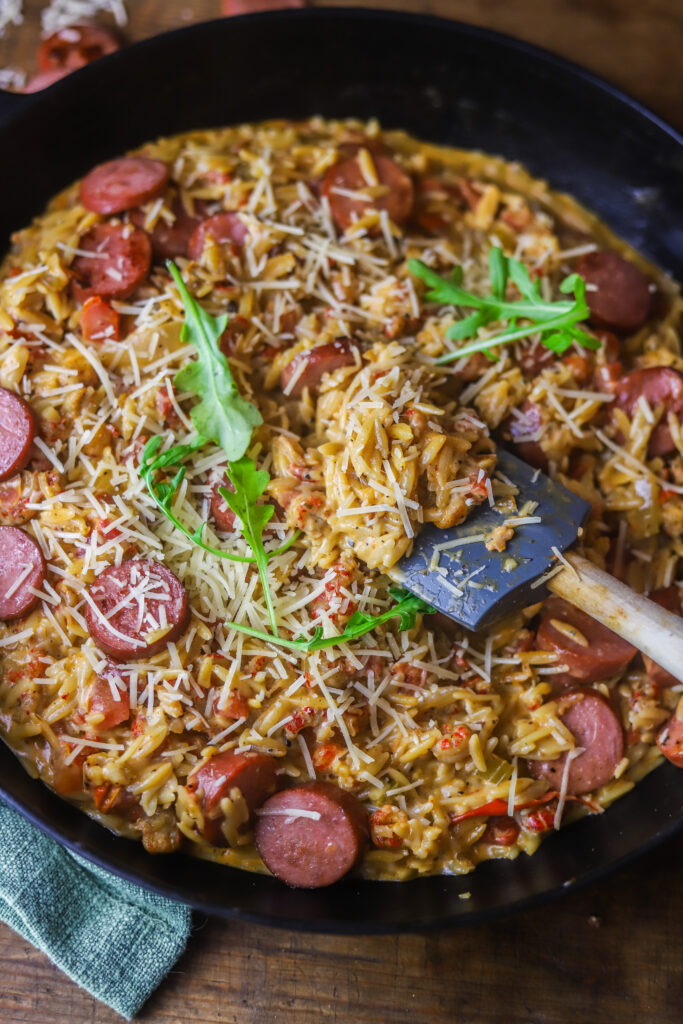 This Cajun creamy orzo recipe. It's so delicious. It's a spicy tomato base with crawfish tails. Add your orzo with some broth and let it all cook until your pasta is nice and tender. Fold in heavy cream, parmesan and browned smoked sausage. This one-pot meal is so simple and delicious and takes less than 30 to make. 