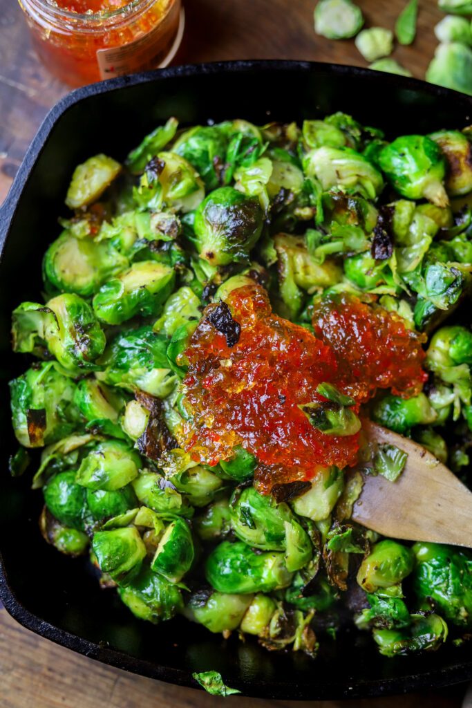 These pepper jelly caramelized brussel sprouts have become a favorite around here. They only require two ingredients along with some salt and pepper and that's it. You'll sauté the brussel sprouts in cast iron, then remove from heat and stir in some spicy pepper jelly. Taking less than 10 minutes to make, you seriously can't beat them. Plus, they are amazingly delicious.