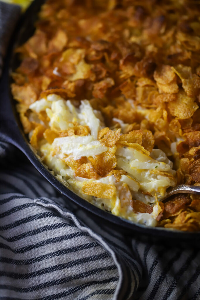 These old-fashioned funeral potatoes aka cheesy potato casserole. Perfect for a potluck or any occasion. I think about church gatherings when I think of these. This is just a bag of frozen hashbrown potatoes, an easy homemade cream of chicken all folded in with cheddar cheese and topped with a buttery cornflake topping. You seriously cannot beat this potato recipe. 