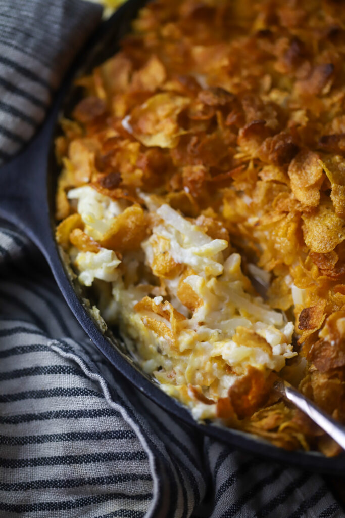 These old-fashioned funeral potatoes aka cheesy potato casserole. Perfect for a potluck or any occasion. I think about church gatherings when I think of these. This is just a bag of frozen hashbrown potatoes, an easy homemade cream of chicken all folded in with cheddar cheese and topped with a buttery cornflake topping. You seriously cannot beat this potato recipe. 