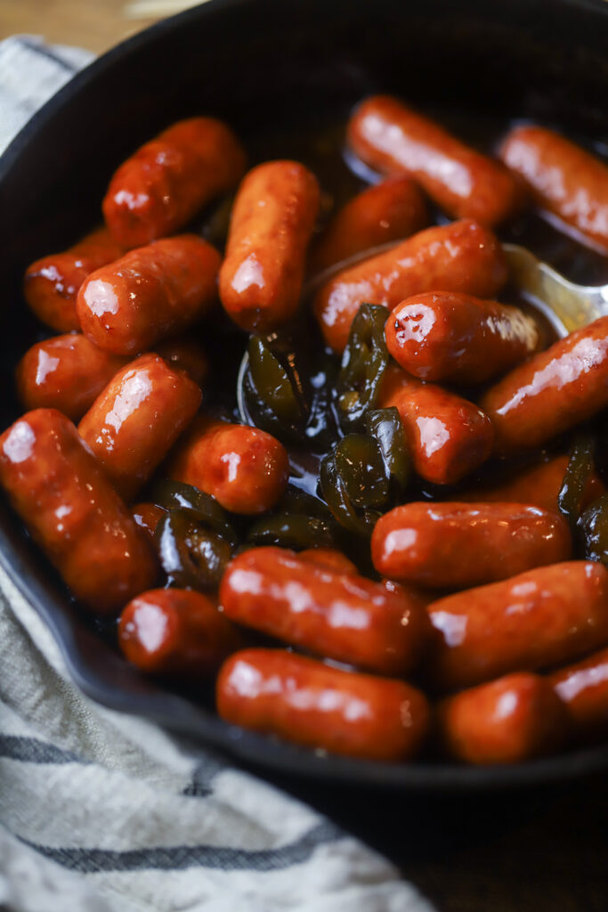 These BBQ lil smokes with candied jalapenos. The perfect appetizer for any function. This is just like a normal lil smokies recipe with grape jelly, BBQ sauce, brown sugar, and of course a bottle of candied jalapenos. This is the perfect sweet and spicy appetizer and I'll show you two different ways you can make them. 