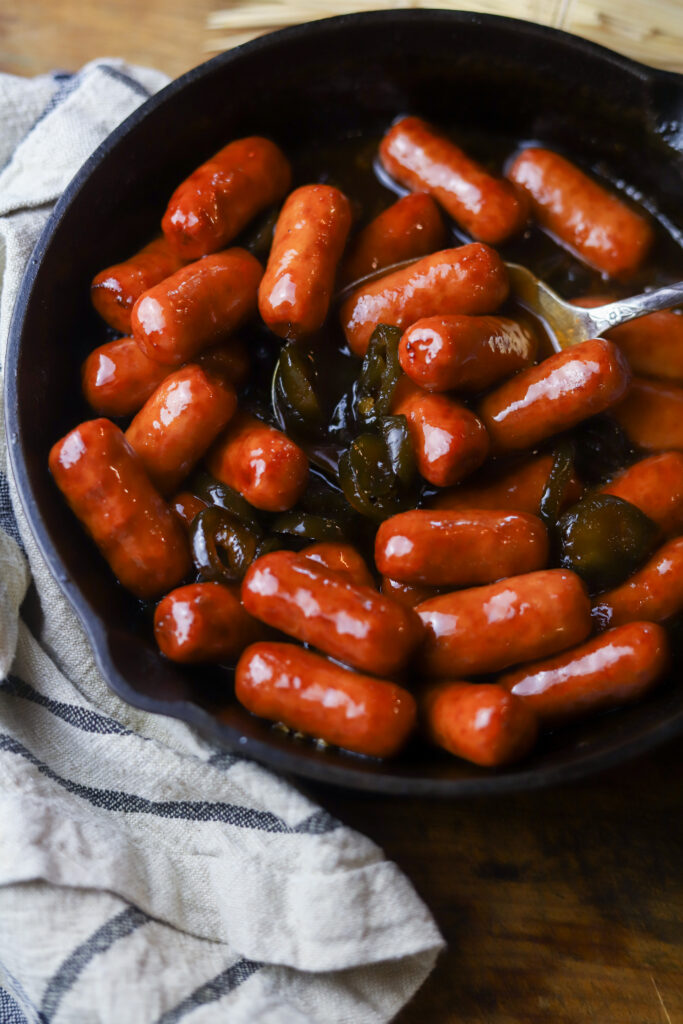 These BBQ lil smokes with candied jalapenos. The perfect appetizer for any function. This is just like a normal lil smokies recipe with grape jelly, BBQ sauce, brown sugar, and of course a bottle of candied jalapenos. This is the perfect sweet and spicy appetizer and I'll show you two different ways you can make them. 