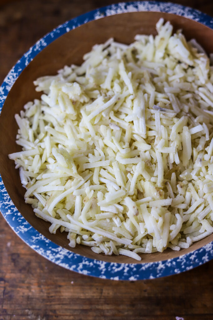 These old-fashioned funeral potatoes aka cheesy potato casserole. Perfect for a potluck or any occasion. I think about church gatherings when I think of these. This is just a bag of frozen hashbrown potatoes, an easy homemade cream of chicken all folded in with cheddar cheese and topped with a buttery cornflake topping. You seriously cannot beat this potato recipe. 