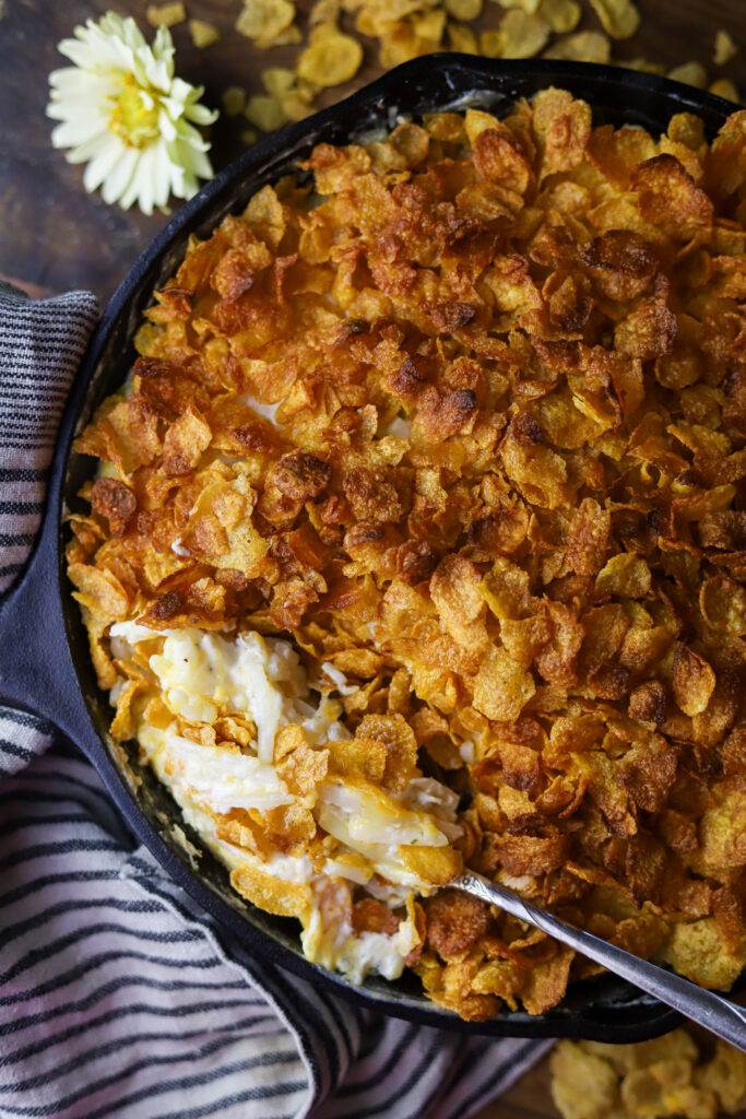 These old-fashioned funeral potatoes aka cheesy potato casserole. Perfect for a potluck or any occasion. I think about church gatherings when I think of these. This is just a bag of frozen hashbrown potatoes, an easy homemade cream of chicken all folded in with cheddar cheese and topped with a buttery cornflake topping. You seriously cannot beat this potato recipe. 