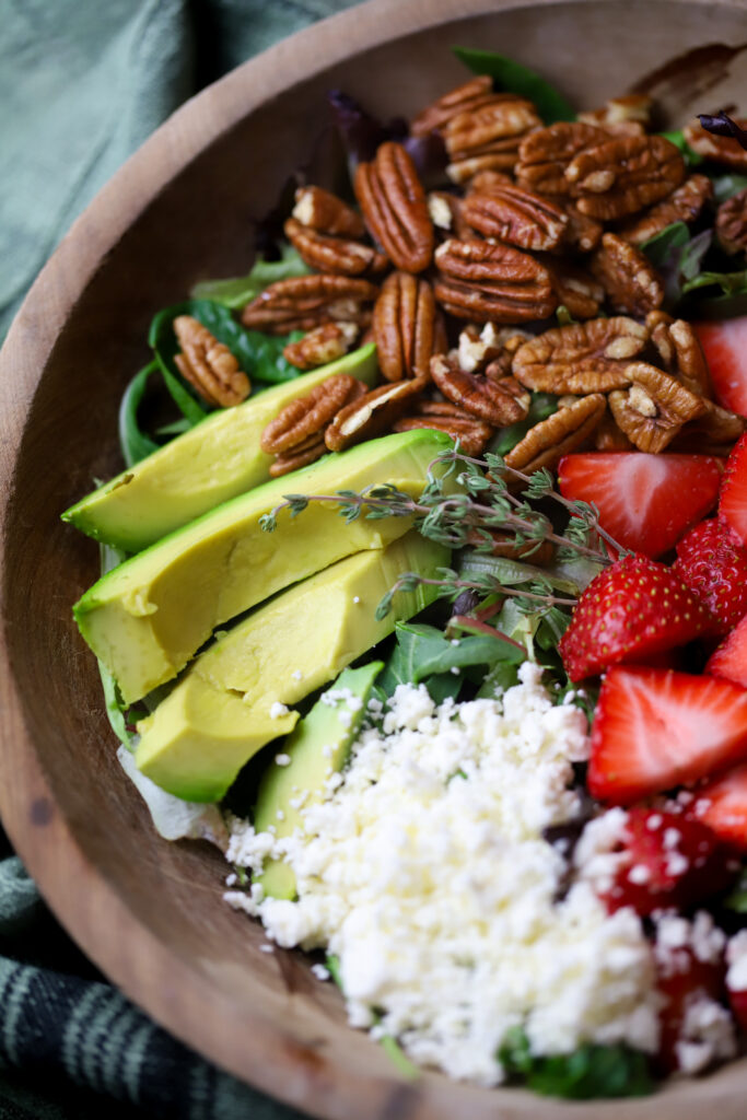 This strawberry pecan salad with pepper jelly vinaigrette is literally so good. You can also make this salad any time of year. All you’re going to need is a bed of greens, some strawberries, feta cheese, roasted pecans and then make this homemade vinaigrette made with pepper jelly. It’s so simple to make and delicious.