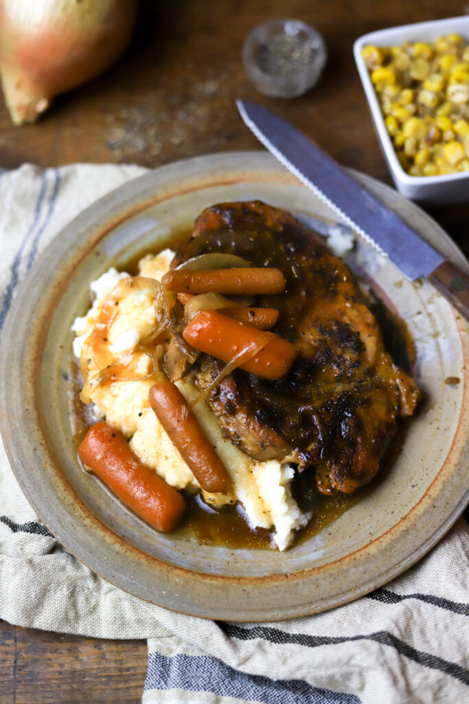 I love these bone-in smothered crockpot pork chops. These are such an easy and delicious comfort food. I started by searing my porkchops in a skillet then added them to my crockpot with some gravy mix, a can of gravy, and some beef consommé. Add some veggies like onions and carrots to complete it. This recipe tastes best over rice or mashed potatoes. You can't beat this comfort dish.