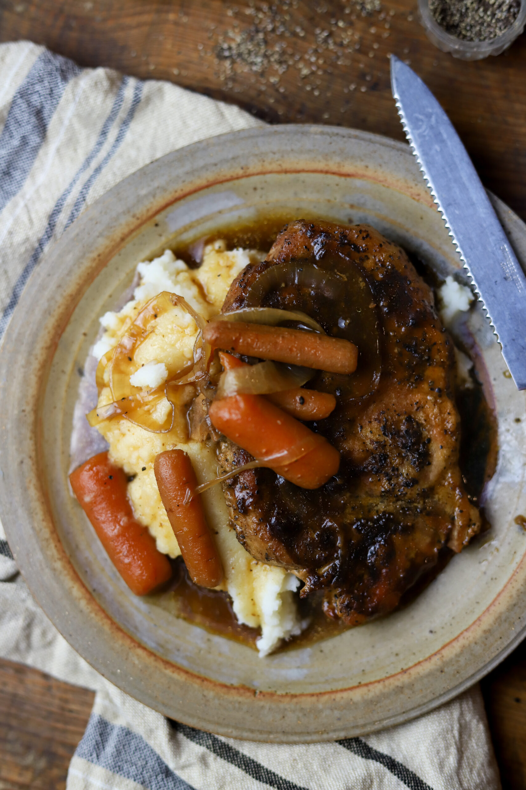 I love these bone-in smothered crockpot pork chops. These are such an easy and delicious comfort food. I started by searing my porkchops in a skillet then added them to my crockpot with some gravy mix, a can of gravy, and some beef consommé. Add some veggies like onions and carrots to complete it. This recipe tastes best over rice or mashed potatoes. You can't beat this comfort dish.