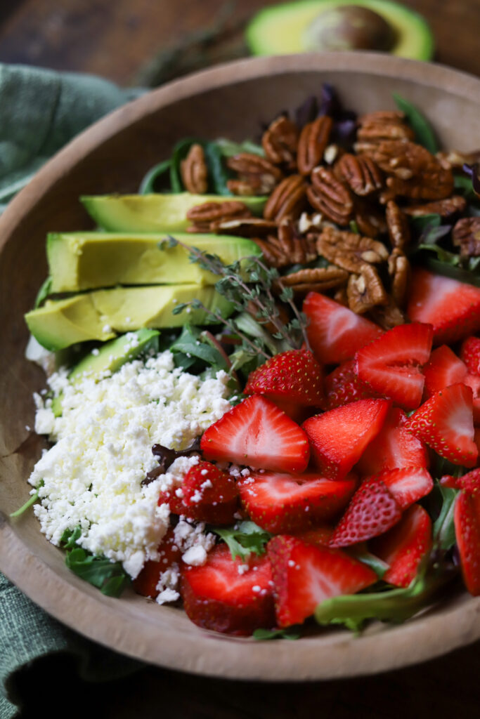 This strawberry pecan salad with pepper jelly vinaigrette is literally so good. You can also make this salad any time of year. All you’re going to need is a bed of greens, some strawberries, feta cheese, roasted pecans and then make this homemade vinaigrette made with pepper jelly. It’s so simple to make and delicious.