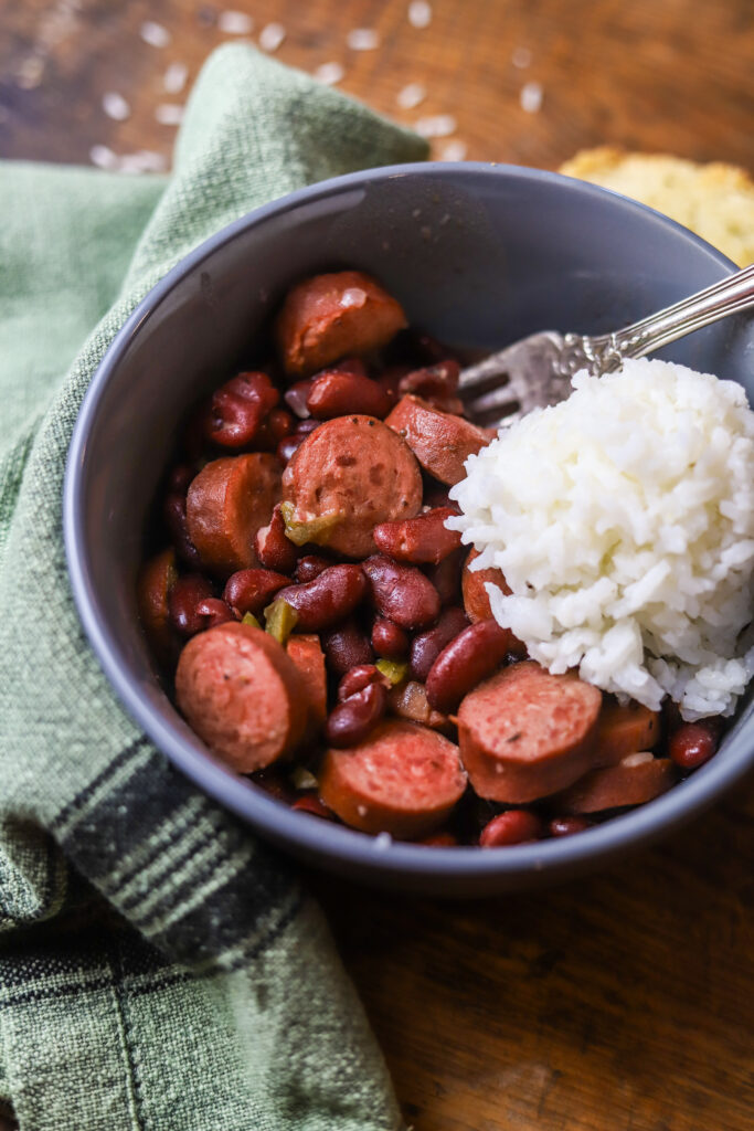 You'll love this easy crockpot red beans and rice. This is the easiest comfort food. You'll need some canned red kidney beans, smoked sausage, some Cajun holy trinity, and of a few seasonings. Let it slow cook all day on high. Serve it with white rice and that's it. This is perfect for a crowd or just as an easy dinner at home. 